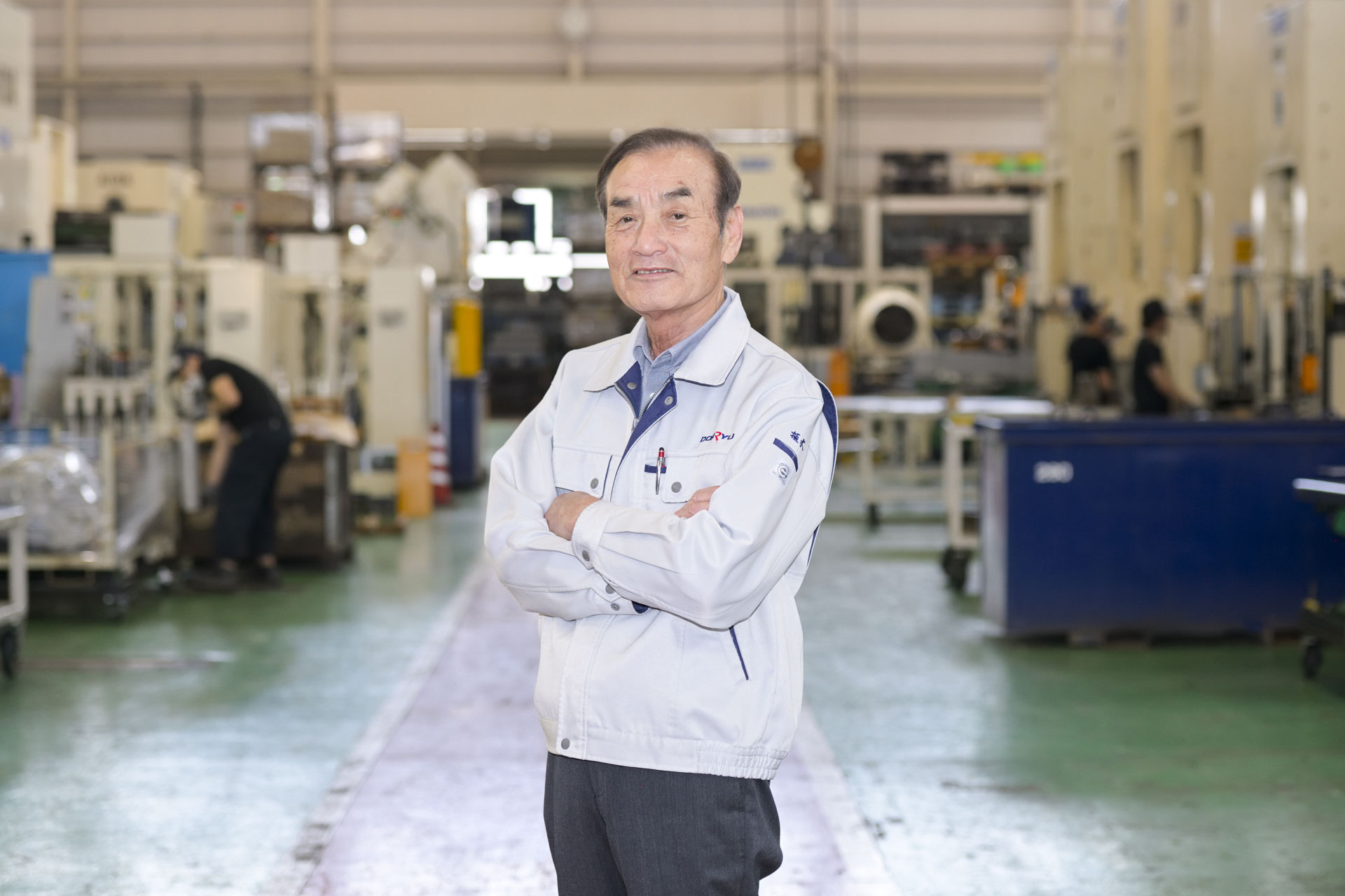 工場内で笑顔で立つ代表取締役