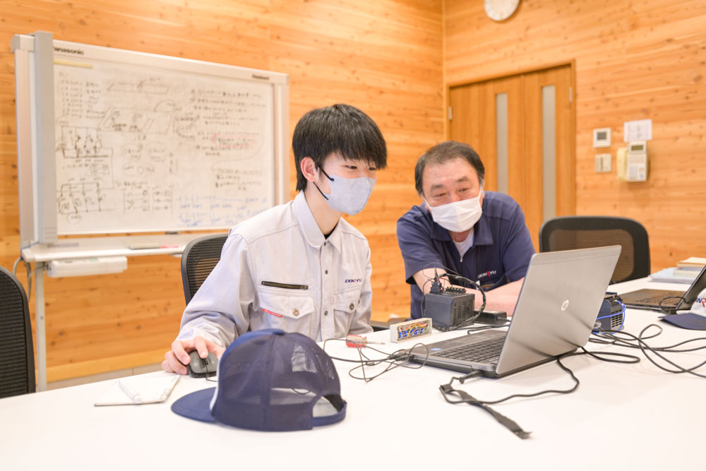 会議室にて、ベテラン社員が新人社員にパソコン操作を指導